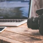 black dslr camera on beige wooden surface